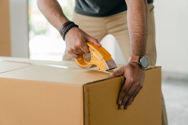 Hands sealing a parcel box for hyperlocal delivery dispatch